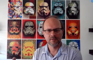 Photograph of Ken Rickard in front of star wars graphics, showing his love of story telling as part of sensemaking for organizational change